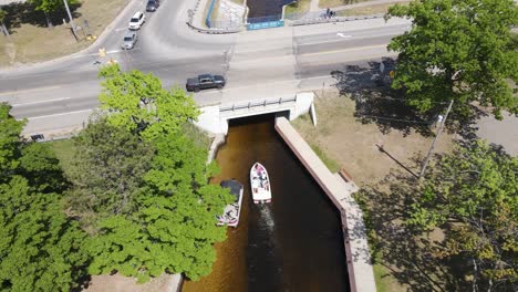 Canal-leading-under-highway-to-connect-two-lakes-in-Micihgan,-aerial-view