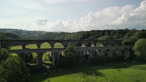 Chirk-Aqueduct-and-Railway-Viaduct-approach,-people-crossing-canal-towpath---aerial-drone-fly-forward-and-valley-reveal---Welsh,-English-border,-Sept-23
