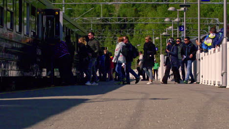 Toma-En-Cámara-Lenta-De-Pasajeros-Haciendo-Cola-Y-Subiendo-A-Un-Tren-En-Una-Estación-De-Tren-En-Un-Día-Soleado