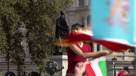 A-woman-with-“Free-Iran”-written-across-her-face-waves-an-Iranian-flag-during-a-protest-rally-in-Trafalgar-Square-marking-the-one-year-anniversary-of-the-death-of-Mahsa-Amini