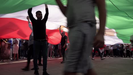 Protestors-push-and-billow-a-giant-Iranian-flag-from-underneath-during-a-protest-rally-in-Trafalgar-Square-marking-the-one-year-anniversary-of-the-death-of-Mahsa-Amini