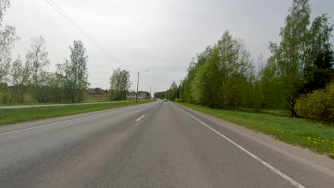 Driving-fast-along-a-serene-road-lined-by-trees-outside-the-city-of-Porvoo,-Finland