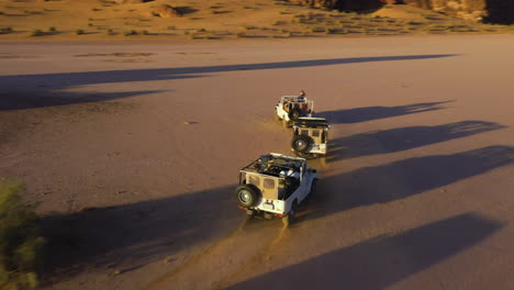 Drone-shot-following-off-road-vehicles,-driving-through-deserts-of-Saudi-Arabia