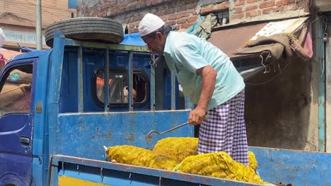 Laborer-man-from-Bangladesh-on-truck-managing-big-ingredients-sacks-in-the-busy-street