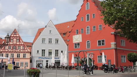 Gente-Caminando-Por-La-Calle-Schrannenstrasse-Con-Fuente-Marktbrunnen-En-Nordlingen,-Alemania