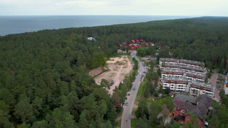 Aerial-view-of-Stegna-Village-with-apartment-blocks-and-cars-on-road-between-forest---Bay-of-Gdansk-in-background