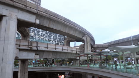 BTS-Skytrain-with-Traffic-sky-walk-area-connects-Siam-Discovery-department-store-and-MBK-Center-over-the-Pathumwan-Intersection-in-evening,-Bangkok-Thailand