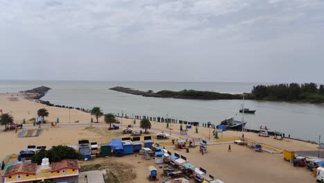 Aerial-view-of-Arasalar-river-estuaries-with-the-Bay-of-Bengal-ocean,-Beach-view-with-tourists-roaming-view-from-the-lighthouse