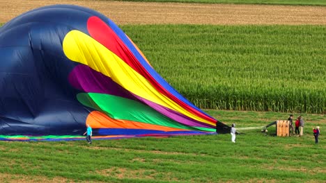 Menschen,-Die-Einen-Bunten-Heißluftballon-Auf-Feldern-Im-Amish-Land-Aufblasen,-Drohnenaufnahme-Aus-Der-Luft