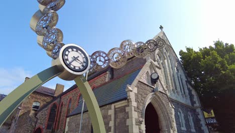 Obras-De-Arte-Del-Reloj-Con-La-Iglesia-Restaurada-Detrás-En-El-Casco-Antiguo-De-La-Ciudad-De-Waterford,-Irlanda,-En-Un-Brillante-Día-De-Verano