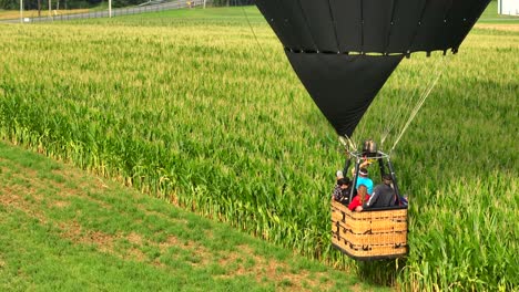 Gente-Despegando-Un-Globo-Aerostático,-Volando-Muy-Cerca-De-Campos-Agrícolas-Verdes,-Disparo-Aéreo-De-Drones