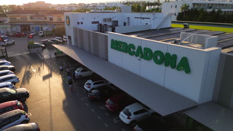 Aerial-view-of-Mercadona-grocery-store-parking-with-solar-panels-on-the-rooftop,-green-energy-business-in-Marbella-Estepona-Malaga-Spain,-Spanish-supermarket,-4K-static-shot