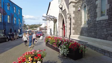 Old-town-Waterford-City-clock-museum-with-bright-flowers-and-people-early-in-summer