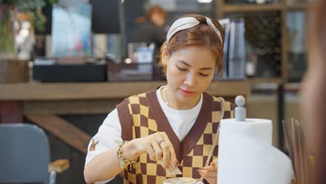 A-Asian-beautiful-girl-putting-sugar-in-a-cup-of-coffee,-preparing-to-enjoy-the-taste