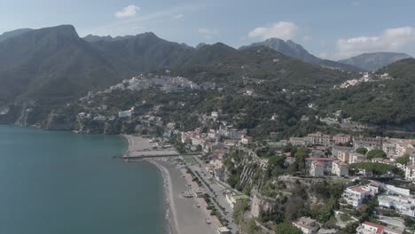 slow-reveal-Ariel-shot-of-a-beautiful-sandy-beach-with-high-and-tall-mountains-in-the-background-in-a-small-and-touristy-town-in-the-heart-of-italy