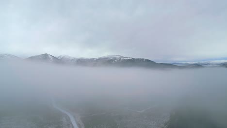Un-Dron-Aéreo-Captura-La-Encantadora-Niebla-Baja-Y-Densa-Que-Cubre-Las-Tierras-Altas-De-Escocia,-Revelando-Majestuosas-Montañas-Que-Emergen-De-La-Niebla.