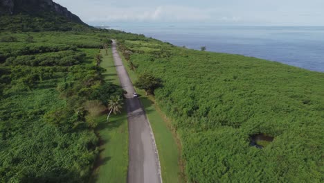 Drone-shot-of-car-driving-along-Banzai-Cliff,-Saipan,-USA