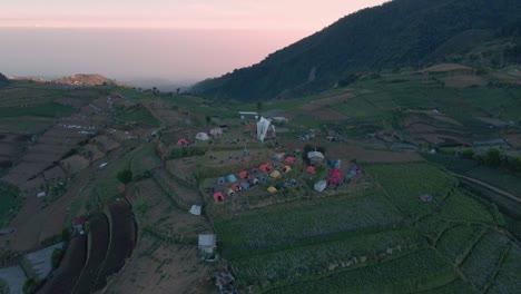 Aerial-view-of-Skoter-Hill-in-Dieng-Plateau-with-group-of-people-sleeping-on-slope-in-tent-at-sunrise-in-Indonesia