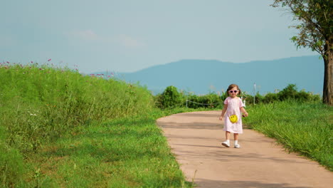 Adorable-Little-Girl-Walks-Backwards-on-Road-in-Mountain-Highland-Park-in-Anseong-Farmland
