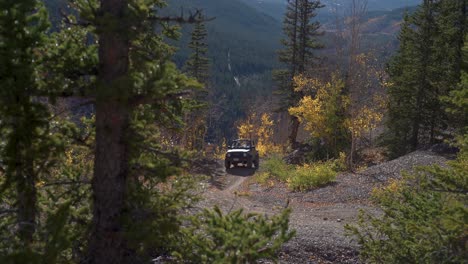 A-man-and-his-dog-in-a-vintage-4x4-ascends-the-winding-mountain-road,-the-air-is-filled-with-the-crisp,-invigorating-scent-of-autumn-leaves
