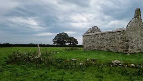 The-ruins-of-Capel-Lligwy-on-rural-Moelfre-countryside,-Anglesey,-North-Wales,-Right-panning-slow-slot
