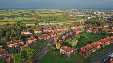 UK-urban-neighborhood:-Aerial-view-of-Yorkshire's-council-estate,-characterized-by-red-brick-architecture,-morning-sunlight,-and-a-bustling-street-scene