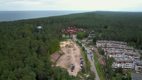 Aerial-backwards-shot-of-woodland-and-Stegna-village-with-buildings-and-Baltic-sea-in-background,-Poland