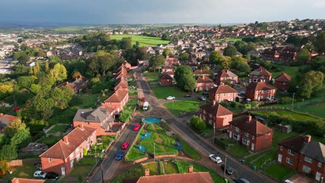 UK-urban-scene:-Aerial-drone-video-of-Yorkshire's-red-brick-council-estate-in-the-warm-morning-sunlight,-highlighting-homes-and-people-on-the-streets