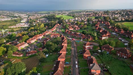 UK-urban-housing:-Red-brick-council-estate-in-Yorkshire,-captured-from-above-by-a-drone-in-the-morning-sunlight,-revealing-homes-and-people-on-the-streets