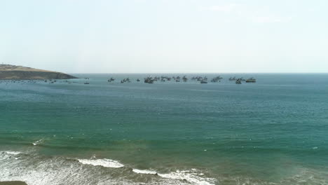 Aerial-view-flying-over-a-beach,-ships-moored-on-the-coastline-of-Huacho,-Peru