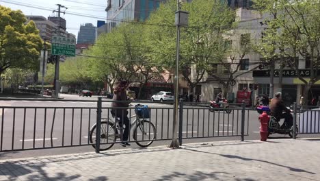 Chinese-woman-on-a-bike-in-the-streets-of-Shanghai,-China-in-slow-motion