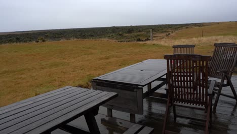 Gliding-shot-of-wet-deck-with-chairs-and-tables-on-overcast-day-in-Iceland
