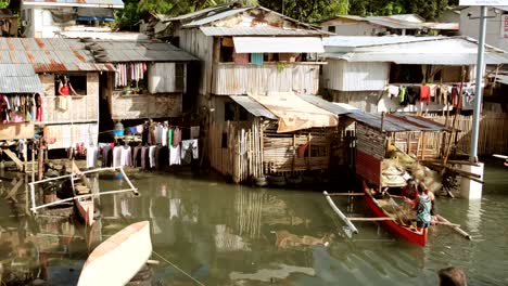 Die-Fischer-Angelten-Fische-Aus-Dem-Netz-Im-Fischerboot,-Während-Das-Haus-Auf-Dem-Wasser-Schwamm