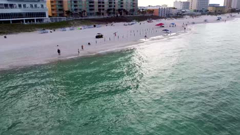 Morning-aerial-beach-view-coastal-aerial-footage-while-the-beach-service-man-is-setting-up-the-umbrellas-and-chairs-on-the-beach