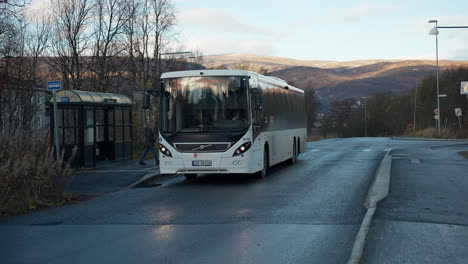Parada-De-Autobús-En-El-Cobertizo-De-Espera-Con-Viajeros-Durante-La-Puesta-De-Sol-En-Tromso,-Noruega
