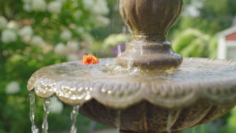 Nahaufnahme-Eines-Gartenbrunnens-Mit-Herabtropfendem-Wasser,-Umgeben-Von-Blühenden-Blumen
