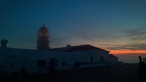 Leuchtturm-Am-Cabo-De-São-Vicente-In-Betrieb,-Während-In-Der-Ferne-Die-Sonne-Untergeht