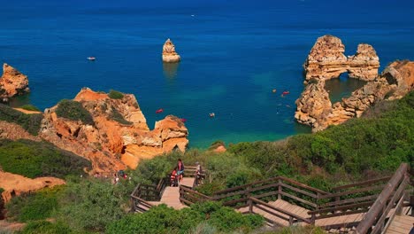 Perspective-view-going-down-the-long-stairs-towards-the-turquoise-waters-of-Praia-do-Camilo-in-Algarve,-Lagos,-Portugal