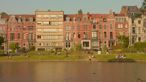 Menschen-Hängen-Am-Ufer-Der-Ixelles-Teiche-Mit-Gebäuden-Im-Hintergrund-In-Brüssel,-Ixelles,-Belgien