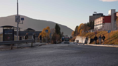 Parada-De-Autobús-En-La-Estación-Con-Pasajeros-Esperando-Durante-La-Puesta-De-Sol-En-Tromso,-Norte-De-Noruega