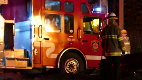 Los-Bomberos-Guían-El-Motor-Hacia-El-Incendio-De-La-Casa,-Las-Llamas-Se-Reflejan-En-El-Vehículo