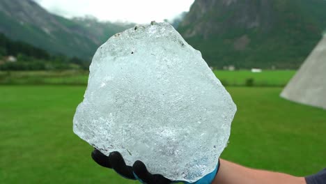 Man-holding-glacial-ice-in-gloved-hand-outside-Fjaerland-Glacier-Museum,-Norway