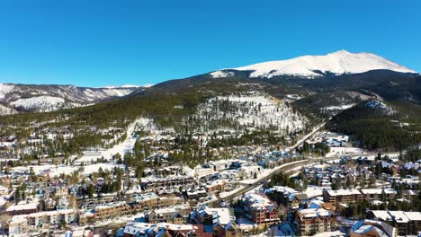Drone-Video-of-Tall-Mountain-in-Breckenridge,-Colorado-with-Cars-Driving-on-Roads-Towards-Snow-Top-Peak-for-Winter-Vacation-Hike
