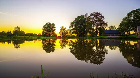 Zeitraffer-Des-Sonnenuntergangs-Auf-Dem-Land-Mit-Faszinierenden-Pastellfarben,-Die-Sich-Auf-Einem-Ruhigen-See-In-Lettland-Spiegeln