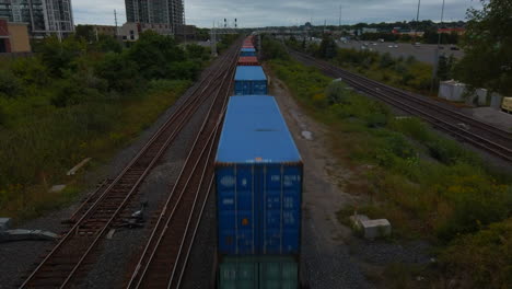 Wide-shot-looking-down-at-a-freight-train-passing-underneath-a-bridge