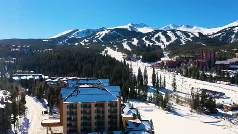 Ski-Resort-Hotel-in-Breckenridge-Colorado,-Aerial-Drone-View-with-Mountains-and-Snow-Covered-Trails-in-Winter-Outdoor-Forest