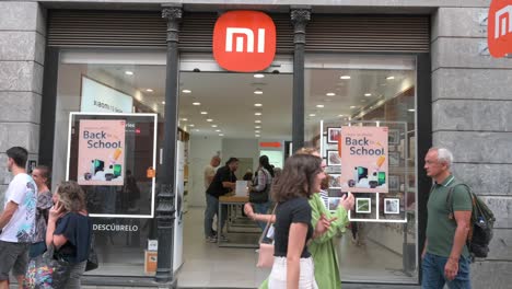 Kunden-Kaufen-Im-Flagship-Store-Des-Chinesischen-Multinationalen-Technologie--Und-Elektronikherstellers-Xiaomi-Ein,-Während-Fußgänger-über-Den-Laden-Laufen