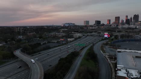 Luftaufnahme-Des-Freeway-In-Der-Innenstadt-Von-Atlanta-Und-Des-Autobahnkreuzes-Mit-Blick-Auf-Die-Skyline-Gebäude-Im-Hintergrund-Bei-Sonnenuntergang