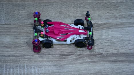 Shadows-playing-around-on-a-pink-and-white-Tamiya-Mini-sports-car-place-on-a-table-in-a-shop-in-Bangkok,-Thailand