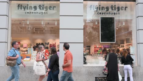 Frauen-Beim-Schaufensterbummel-In-Der-Dänischen-Geschenkkette-Flying-Tiger-Copenhagen,-Im-Laden,-Während-Fußgänger-Am-Rahmen-Vorbeigehen